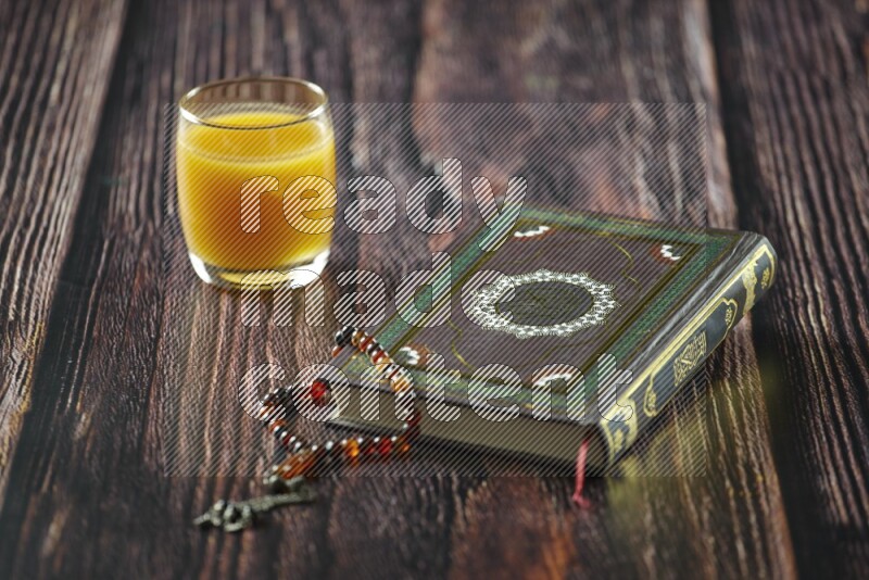 Quran with dates, prayer beads and different drinks all placed on wooden background