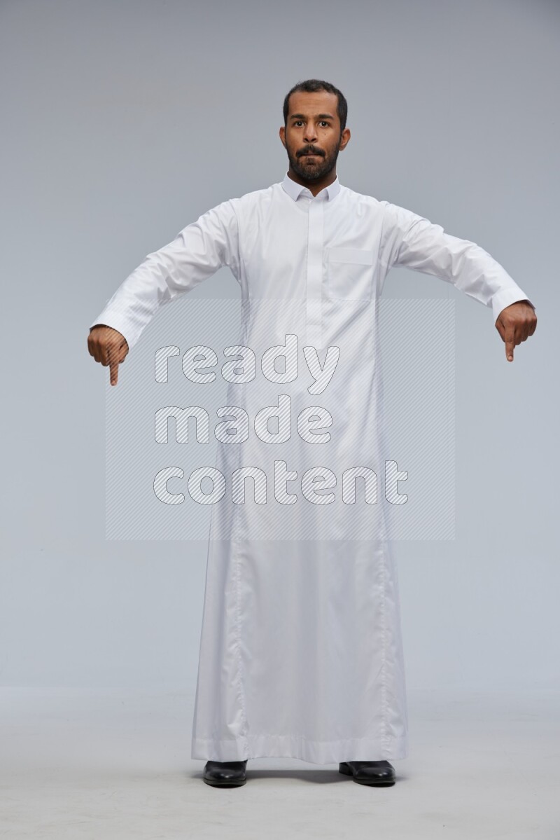 Saudi man Wearing Thob standing interacting with the camera on Gray background