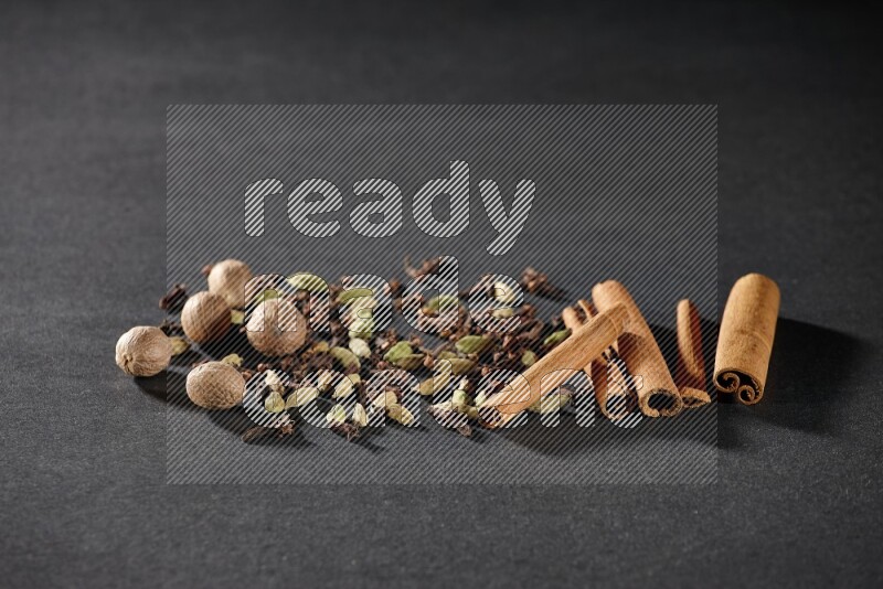 Cardamom, cloves, nutmeg and cinnamon sticks on black flooring