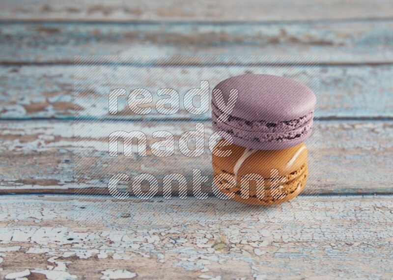 45º Shot of of two assorted Brown Irish Cream, and Purple Blueberry macarons  on light blue background