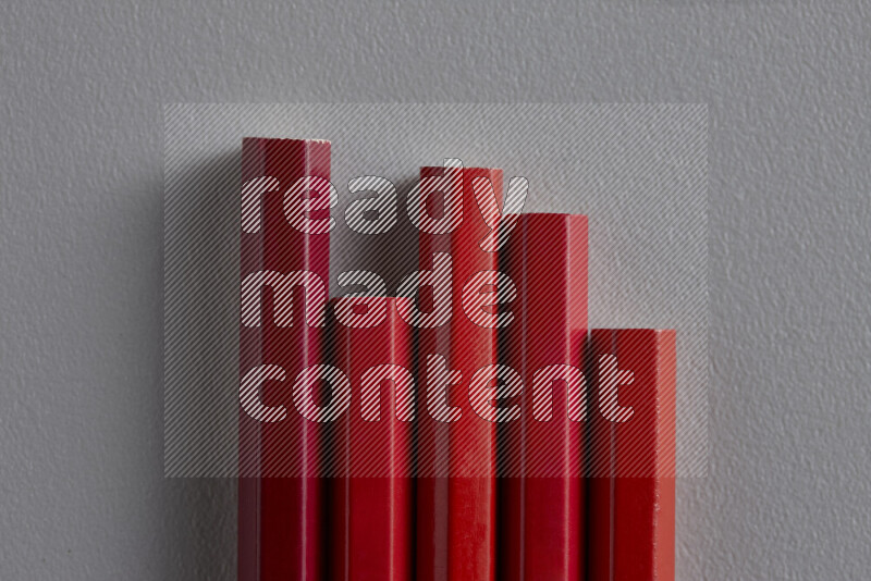 A collection of sharpened colored pencils arranged showcasing a gradient of red hues on grey background