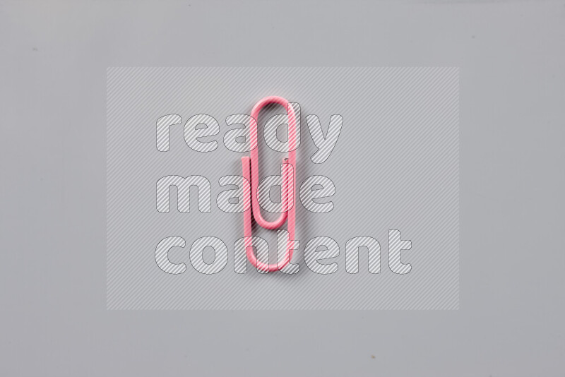 Pink paper clips isolated on a grey background