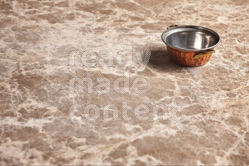 A small copper pot on beige marble background