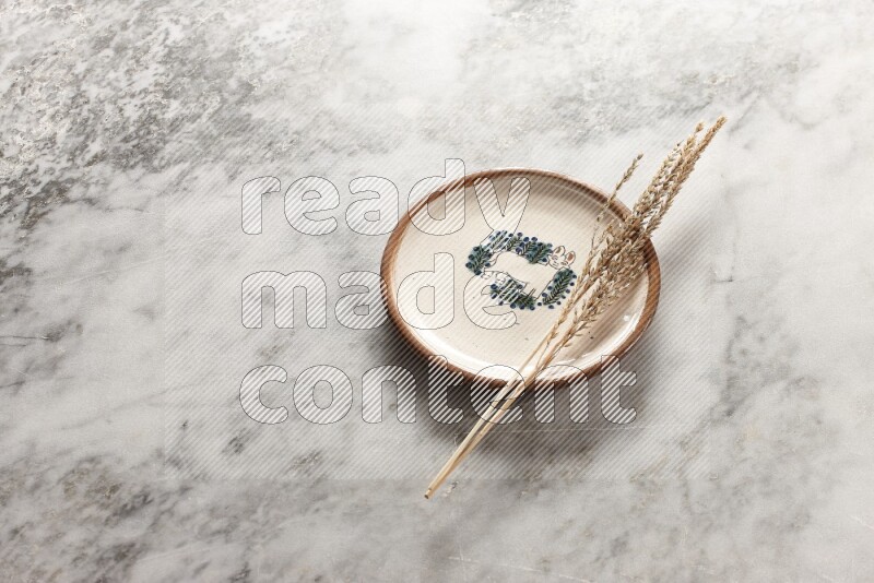 Wheat stalks on decorative pottery plate on grey marble background