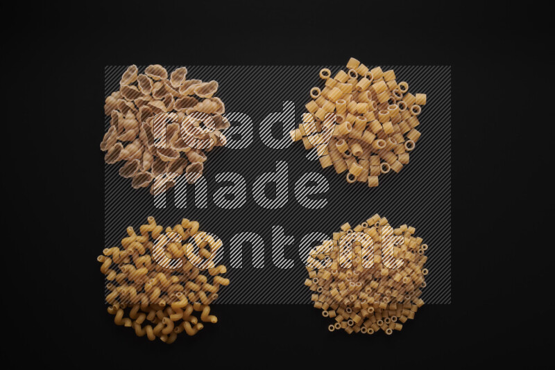Different pasta types in bunches on black background
