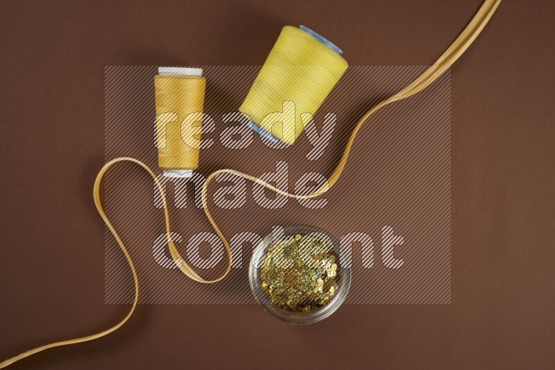 A yellow collection of sewing and tailoring tools arranged on a brown background