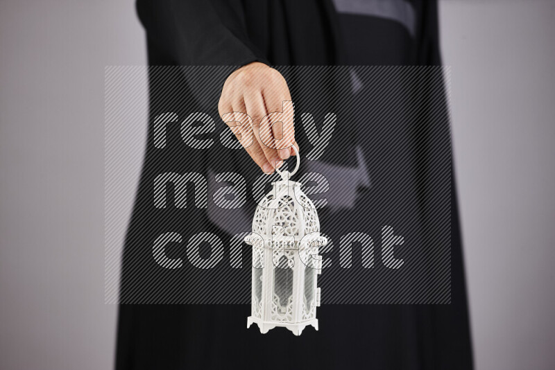 A woman in black abaya holding different ramadan lanterns in different positions