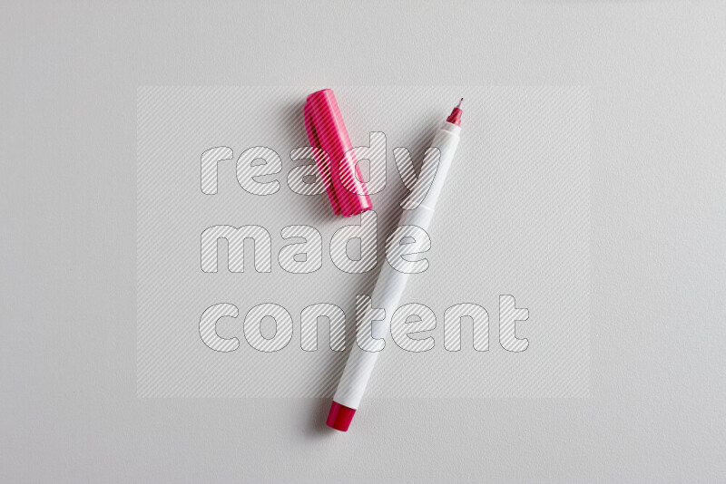 A close-up showing an open single coloring pen with a cap on grey background