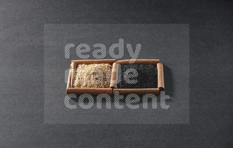2 squares of cinnamon sticks full of sesame and black seeds on black flooring