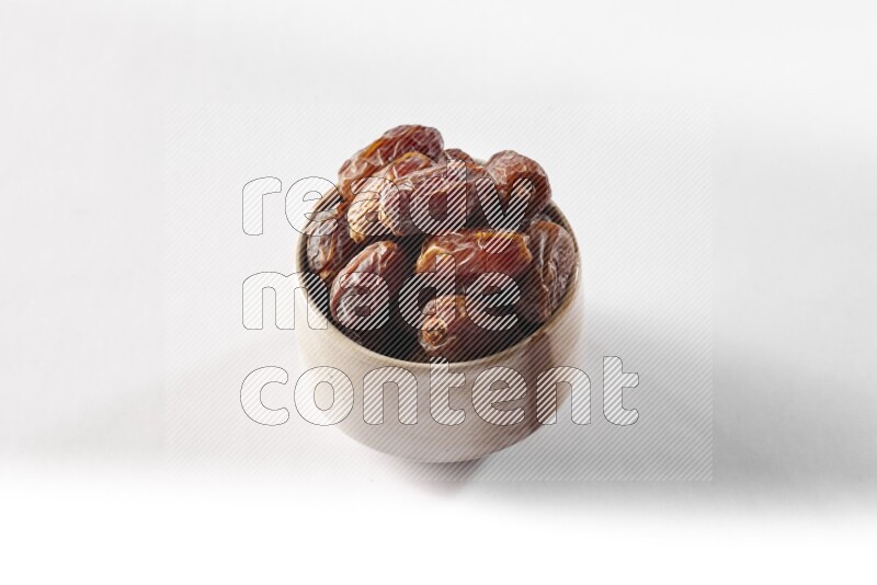 Dates in a beige pottery bowl on white background