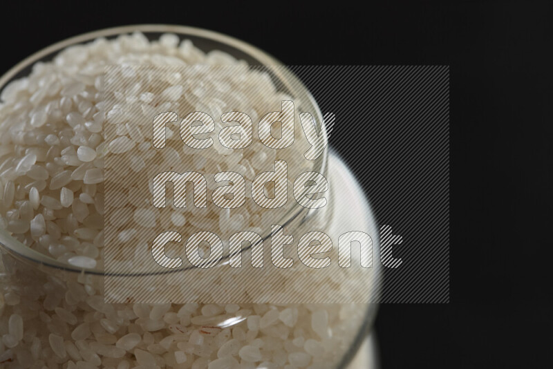 White rice in a glass jar on black background