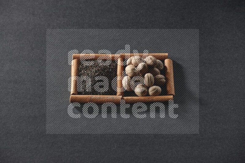 2 squares of cinnamon sticks full of tea and nutmeg on black flooring