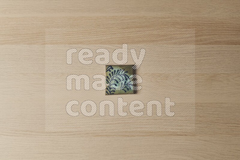 A decorative pottery coaster on light wooden background