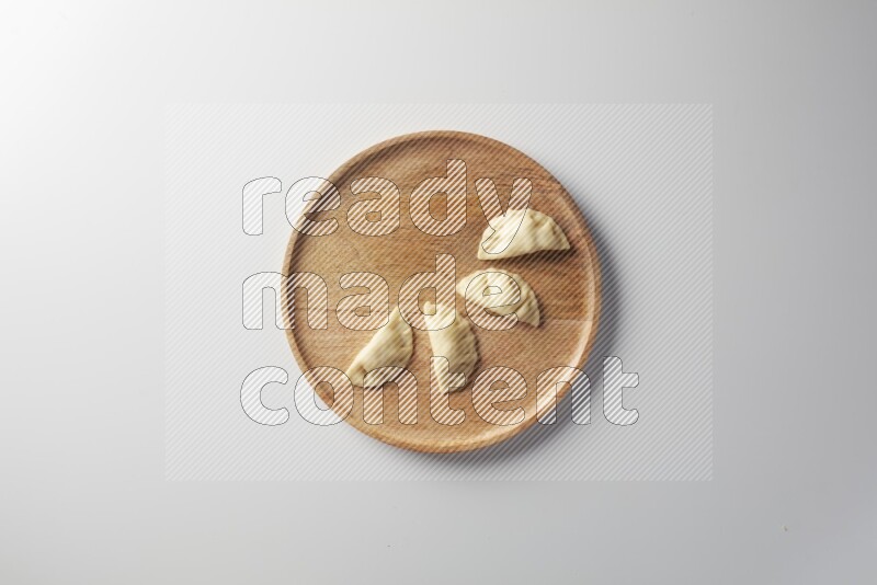 Four Sambosas on a wooden round plate on a white background