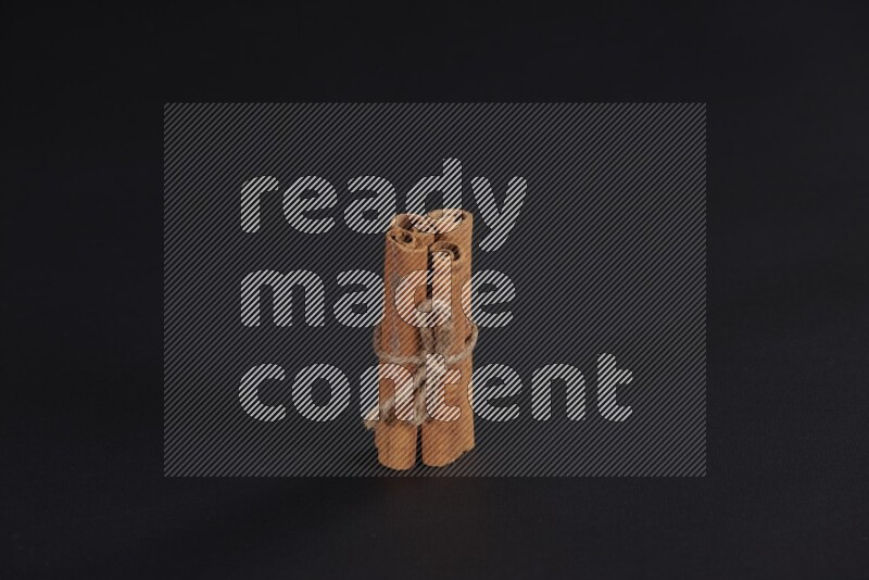 4 أعواد من القرفة مربوطة علي خلفية سوداء