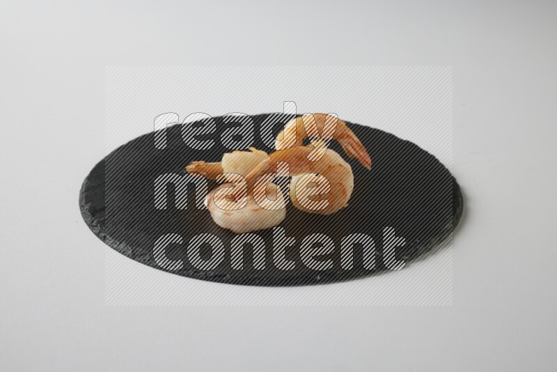 four grilled shrimp  on a black slate direct  on a white back ground