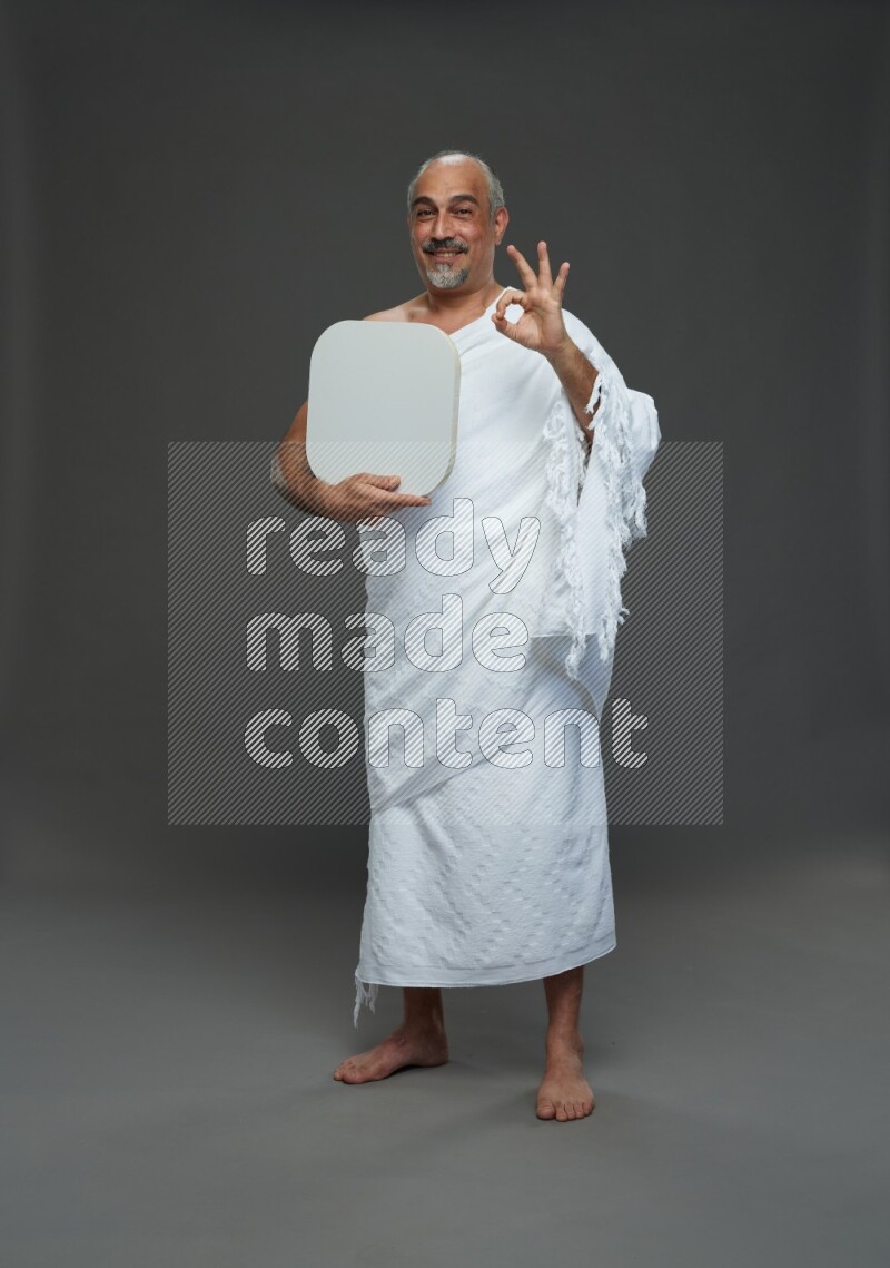 A man wearing Ehram Standing holding social media sign on gray background