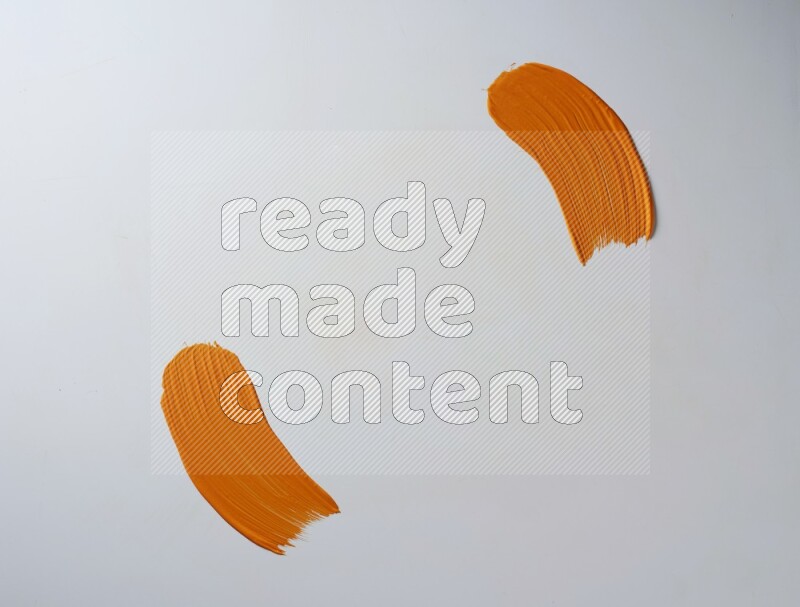 An orange curved painting brush stroke on a white background