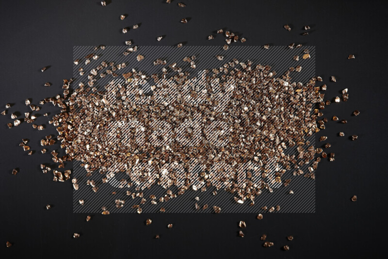 Bronze shimmering fragments of glass scattered on a black background