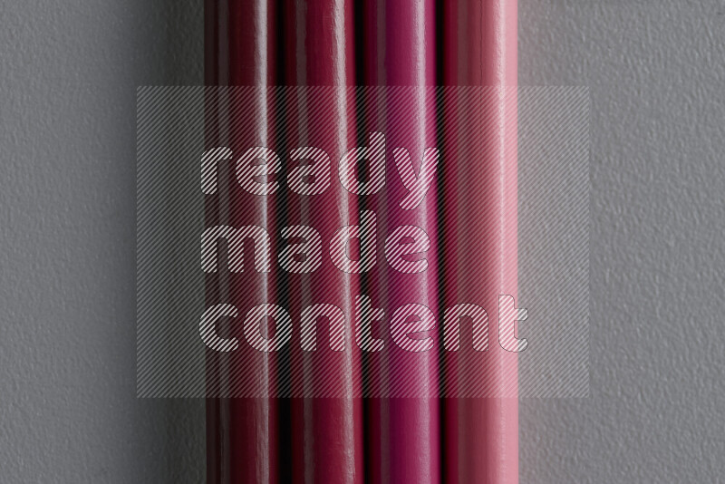 A collection of sharpened colored pencils arranged showcasing a gradient of pink hues on grey background