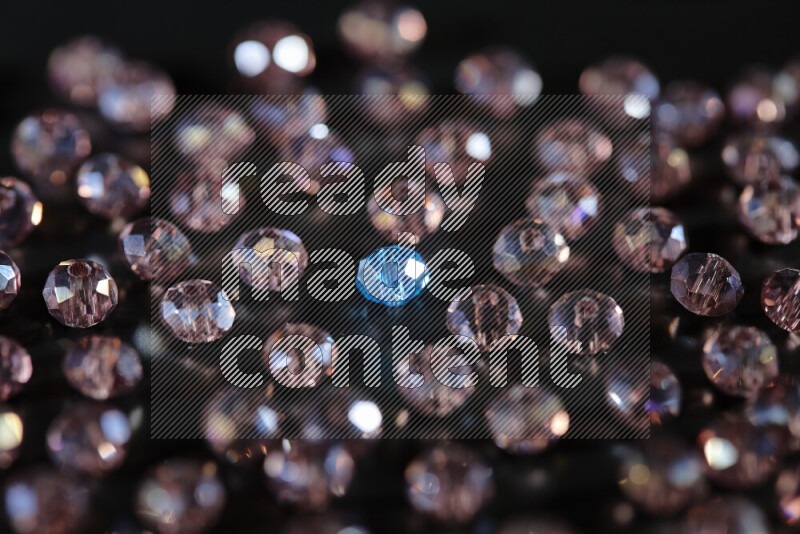 Rose and blue transparent crystal beads scattered on a black background