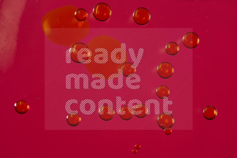 لقطات مقربة لقطرات ألوان مائية صفراء على سطح الزيت على خلفية حمراء