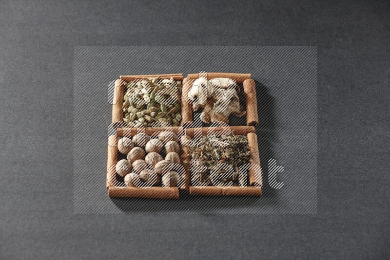 4 squares of cinnamon sticks full of dried basil, cardamom, dried ginger and nutmegs on black flooring