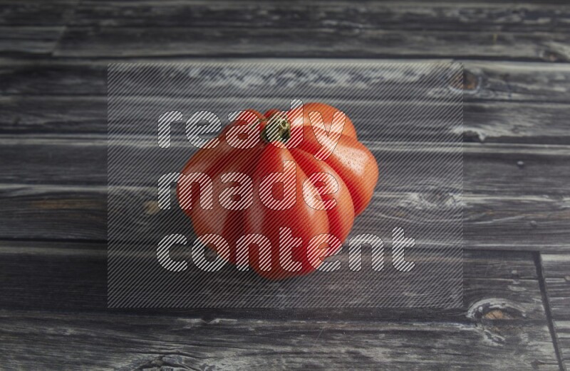 45 degree single heirloom tomato on a textured grey wooden background