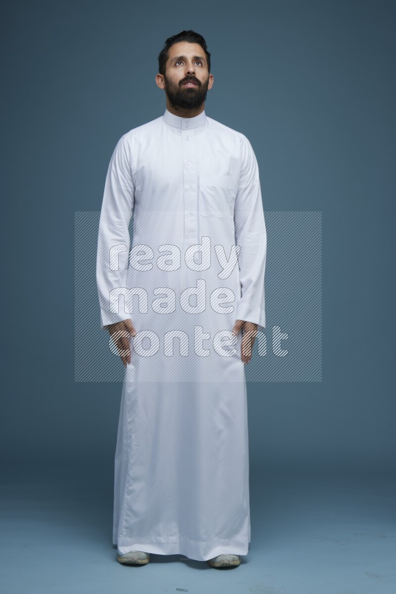A man posing in a blue background wearing Saudi Thob