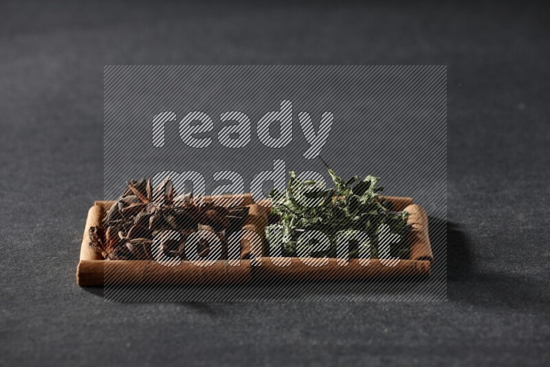 2 squares of cinnamon sticks full of star anise and dried mint leaves on black flooring