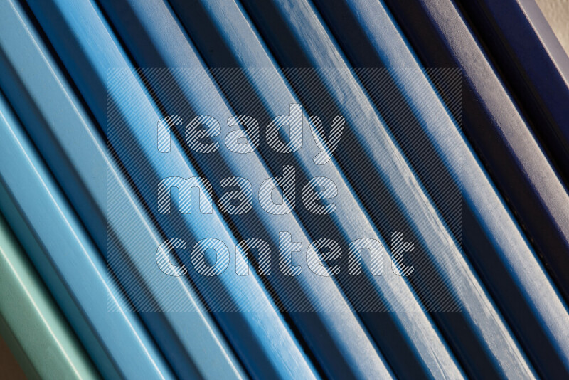 A collection of colored pencils arranged showcasing a gradient of blue hues on grey background