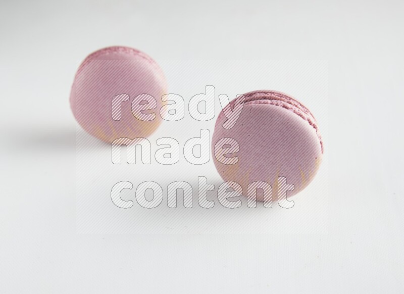 45º Shot of two Purple Strawberry macarons on white background