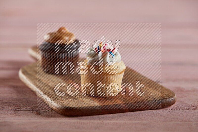 Vanilla mini cupcake topped with cream on a wooden board