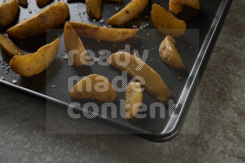 wedges potato in a black stainless steel rectangle tray on grey textured counter top