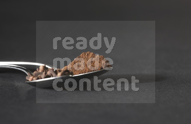 ملعقتان معدنيتان، إحداهما ممتلئة بحبوب القرنفل والأخرى ببودرة القرنفل، على خلفية سوداء