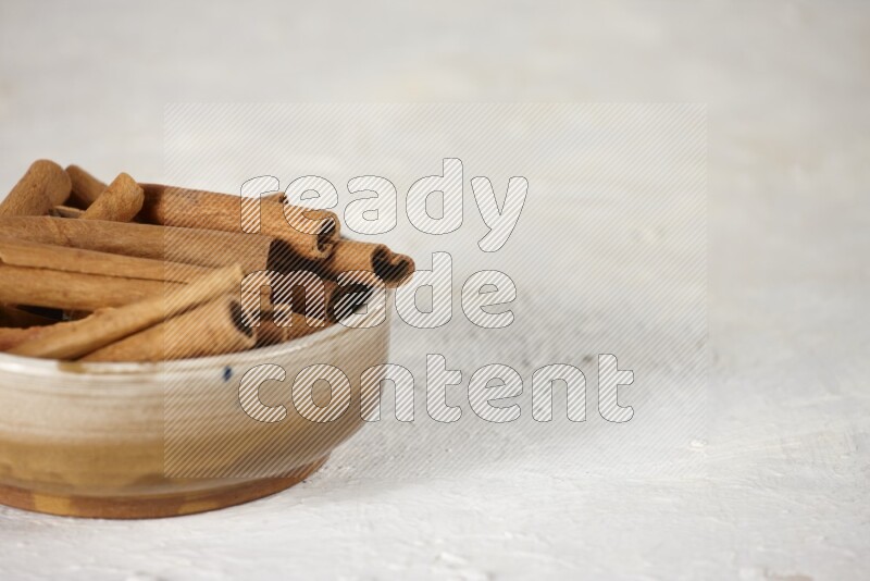 Cinnamon sticks in a ceramic bowl in different angles on white background