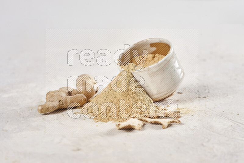 A beige pottery bowl full of ground ginger powder with fallen powder from it on white background