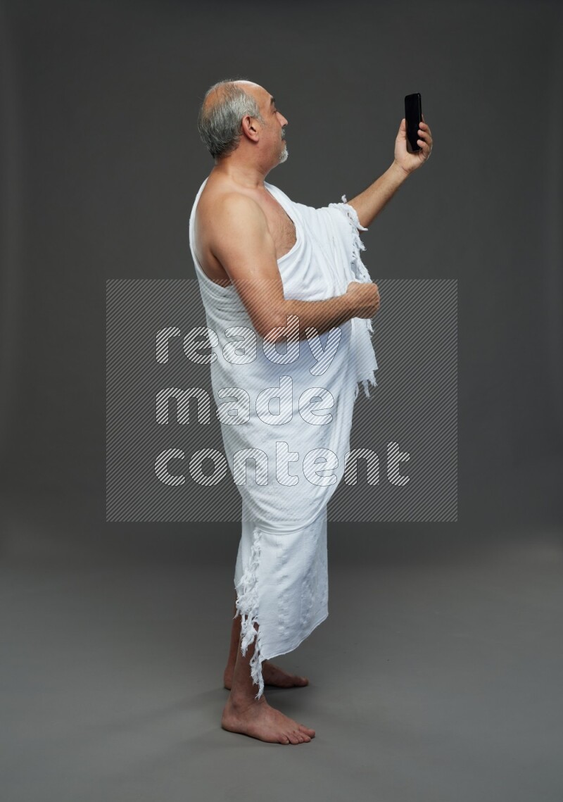 A man wearing Ehram Standing taking selfie on gray background