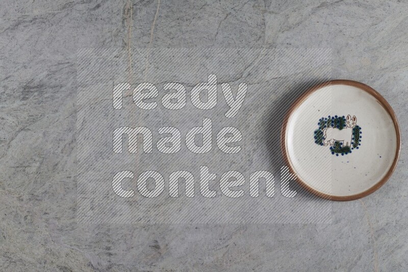 A decorative pottery plate on grey marble background