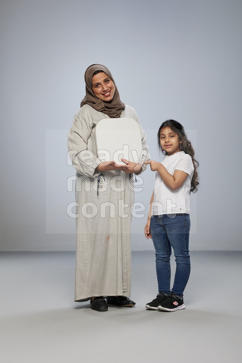 Mom and daughter standing holding social media sign on gray background