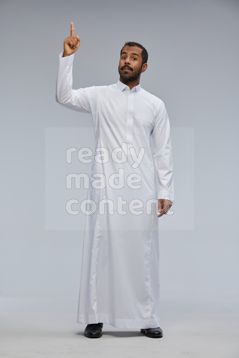Saudi man Wearing Thob standing interacting with the camera on Gray background