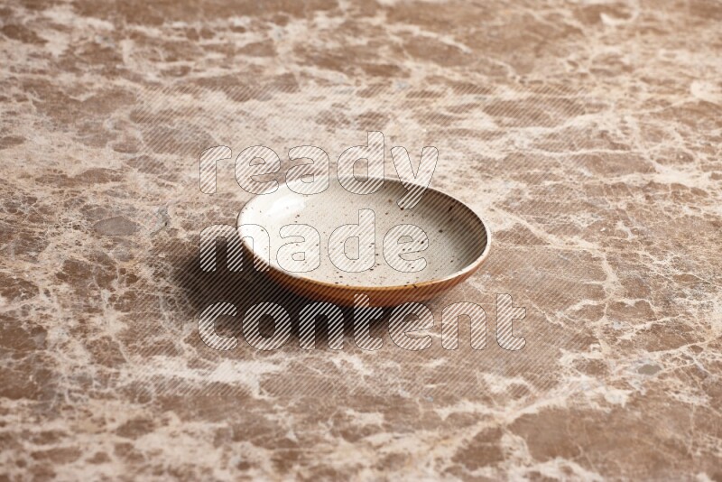A multicolored pottery plate on beige marble background