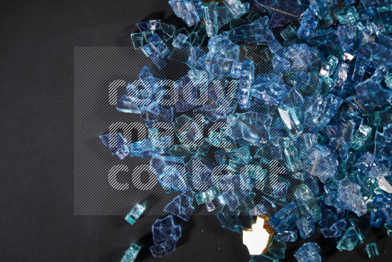 Transparent blue fragments of glass scattered on a black background