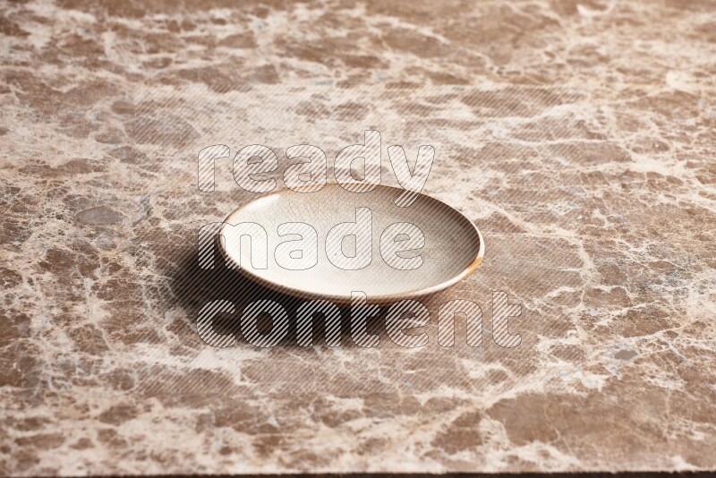 A beige pottery plate on beige marble background