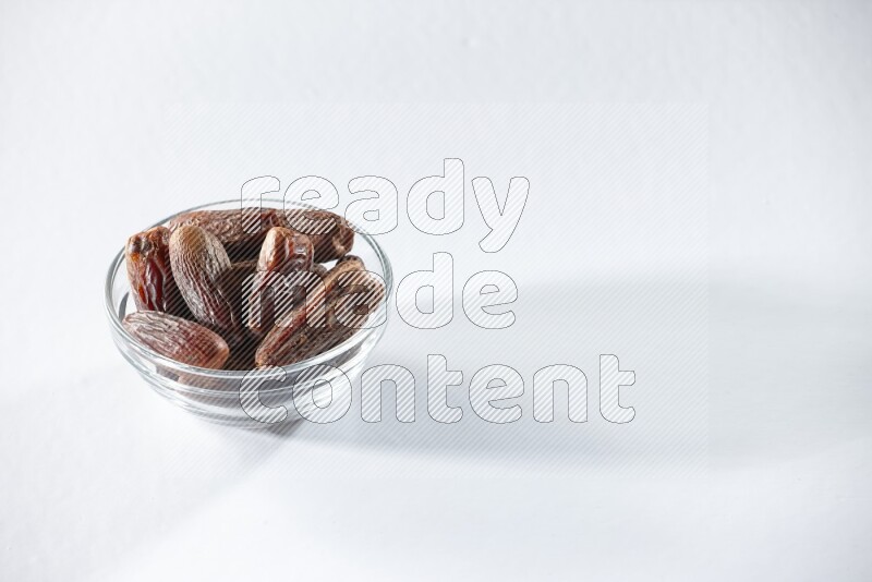 A glass bowl full of dried dates on a white background in different angles