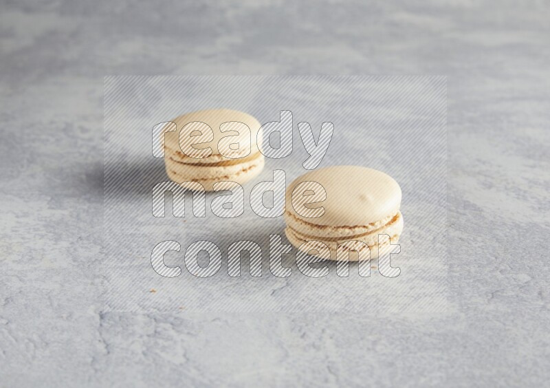 45º Shot of two white marbleCaramel fleur de sel macarons  on white  marble background