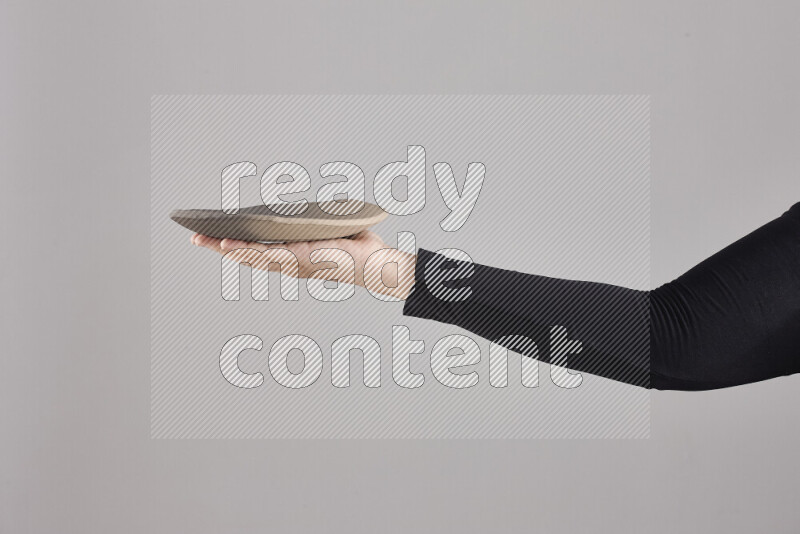 A woman in black abaya holding different pottery essentials in different positions