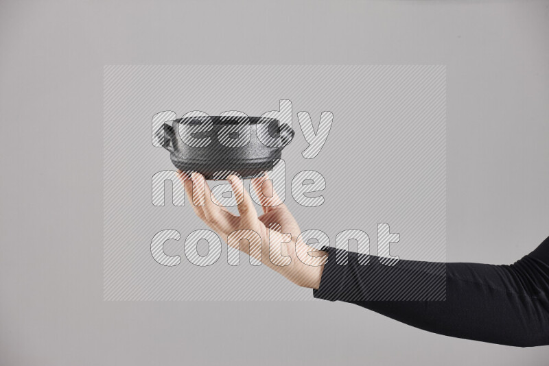 امرأة ترتدي عباءة سوداء تحمل أدوات فخارية مختلفة في أوضاع متعددة