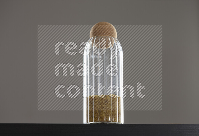 Coarse bulgur in a glass jar on black background