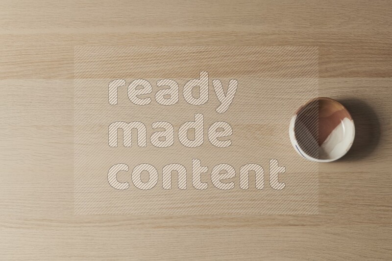 وعاء فخاري متعدد الألوان على خلفية خشبية فاتحة